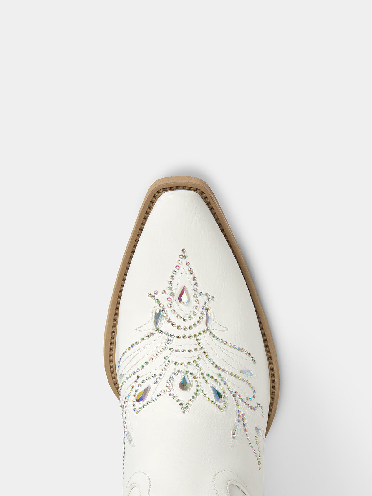 A close-up top-down view of a white western boot toe, featuring decorative silver rhinestone embroidery and a tan leather edge around the pointed toe.