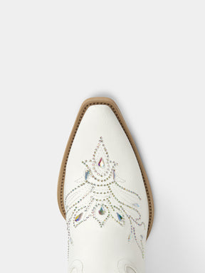 A close-up top-down view of a white western boot toe, featuring decorative silver rhinestone embroidery and a tan leather edge around the pointed toe.