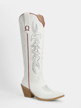 A white leather cowboy boot with silver rhinestone embroidery, a red pull tab, and a brown stacked block heel, shown against a light gray background.