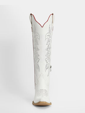 A single white leather cowboy boot shown from the back, featuring silver-toned metallic floral embroidery, a red stitched trim along the collar, and a tan sole.