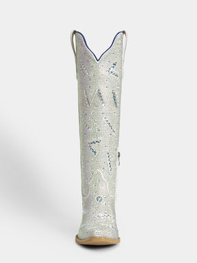A single tall western boot shown from the back on a light gray studio background. The boot is covered in silver rhinestones with blue rhinestone accents and a tan sole.