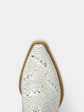 A close-up top-down view of a pointed-toe western boot embellished with dense rhinestones and crystal studs, showing a light beige sole edge against a plain light gray background.